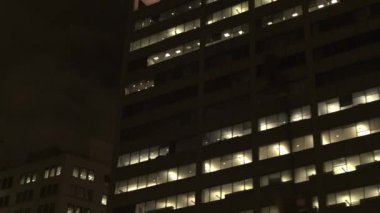 Kadar yakın, düşük görüş açısı: ışıklı windows karanlıkta parlayan ile büyük kurumsal gökdelen geçmiş cadde boyunca sürüş. Geçen büyük ofis binası şehir merkezindeki finans bölgesine, Chicago, ABD