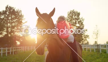Ağır çekim, Close Up, Dof: Güzel sarışın kız sürme ve onun sevgili mare güneş doğarken kucaklayan eyersiz portresi. Kadın Binicilik çarpıcı ata sakin güneşli yaz sabahı güzel