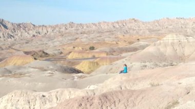 Badlands Ulusal Parkı güneşli günde Güney Dakota'da, ABD çarpıcı manzaranın kayalık dağ yamacında oturan genç kadın uzun yürüyüşe çıkan kimse. Mutlu kız kumtaşı dağ çöl vahşi keşfetmek