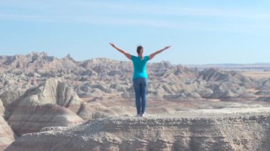 Zevk ve rahatlatıcı güneşli gökyüzü doğru kaldırdı kollarını ile kumtaşı dağın Badlands Ulusal Parkı'nda tepesinde duran Slow Motion mutlu kadın uzun yürüyüşe çıkan kimse. Gezgin keşfetmek Badlands vahşi