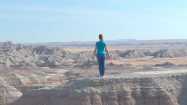 Kum taşı dağın Badlands Ulusal Parkı'nda tepesinde duran, huzur içinde kollarını an tadını güneşli gökyüzüne kadar yükselterek yavaş neşeli kadın uzun yürüyüşe çıkan kimse. Badlands keşfetmek seyahat