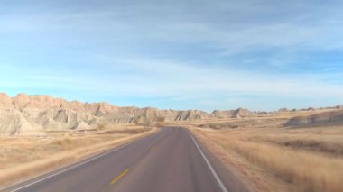 FPV: rocky Kumtaşı Dağları, şaşırtıcı Badlands yatay doğru sarma boş yol boyunca sürüş. Güney Dakota'daki Badlands otlak Çölü seyahat. Yolculuk boyunca Amerika Birleşik Devletleri