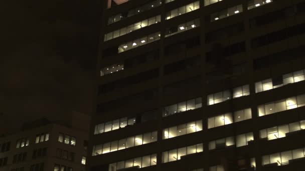 クローズ アップ 低視野角 暗闇の中で輝く明かりのついた窓で過去の巨大な企業の高層ビル街に沿って運転しています 金融地区 ダウンタウン シカゴ 米国で大きなオフィスビルを渡す — ストック動画