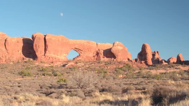 在阳光明媚的傍晚 参观美国犹他州拱门国家公园的令人惊叹的红色岩石形成的游客 太阳热沙漠中的外太空砂岩柱 窗和拱景观形成 — 图库视频影像