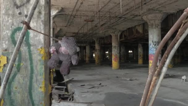 クローズ アップ 怖い汚いテディベア人けのない駐車場ホールで破壊された壁から突き出た棒鋼からぶら下がっています 腐食の遺棄されたフィッシャー自動車工場 デトロイトで放棄された古い駐車場 — ストック動画