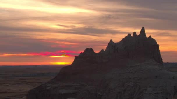 空中美しい無限砂岩と乾いた草草原バッドランズ国立公園の夕暮れ時 広大な草原から赤みを帯びた日の出上昇侵食のロッキー山脈の美しい風景 — ストック動画