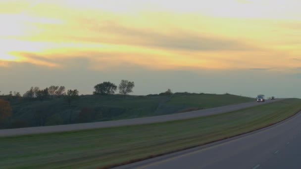 クローズ アップ 貨物コンテナー半トラック黄金の夕日で風光明媚な丘陵風景を介して実行している空のハイウェイに沿って運転です ロマンチックな朝に米国の間で物資の輸送トレーラー — ストック動画
