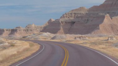 FPV: rocky Kumtaşı Dağları ile şaşırtıcı Badlands peyzaj içine sarma boş yol boyunca sürüş. Güney Dakota'daki Badlands otlak Çölü seyahat. Yolculuk boyunca Amerika Birleşik Devletleri