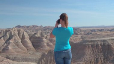 Neşeli genç kadın gezgin doğal Badlands Ulusal Parkı güneşli günde Güney Dakota'da, ABD çekim. Kumtaşı dağ çöl vahşi keşfetmek ve fotoğraf makinesi ile çekim mutlu kız