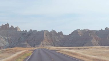 FPV: çarpıcı Badlands manzara kayalık kumtaşı oluşumları ile geride bırakarak boş yol boyunca sürüş. Güney Dakota'daki Badlands Çölü seyahat. Yolculuk boyunca Amerika Birleşik Devletleri.