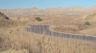 Boş yol kayalık kumtaşı oluşumları, sonsuz Badlands yatay üzerinden kıvrıla kıvrıla. Boş yol Güney Dakota'da çarpıcı Badlands Çölü sarma. Güneşli Türkiye genelinde bir yolculuk.