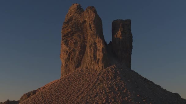空中クローズ アップ 夜明けの美しいイノシシ牙ビュート ランドマーク 黄金の夕日で乾燥した砂漠の火山残骸イノシシの牙 日の出宇宙火山山に輝く最初の木漏れ日 — ストック動画