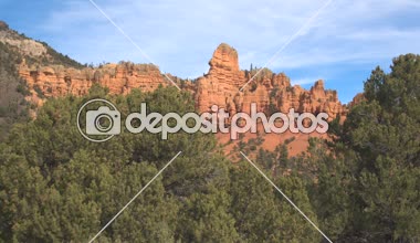 Hava yüksek kırmızı rock kayalıklarla ve Hudu ayağı Bryce Canyon Milli Parkı önünde güneşli Utah, ABD. Bryce Np erozyon oluşumları Kum Çölü ve kumtaşı doğru Çam ağaç tepelerinin üzerinde uçan