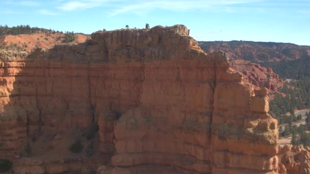 飞越高红色的岩石悬崖 露出空旷的道路蜿蜒进入布莱斯峡谷国家公园在阳光明媚的犹他州 在美国夏日 一条蜿蜒进入布莱斯峡谷的道路鸟瞰图 — 图库视频影像