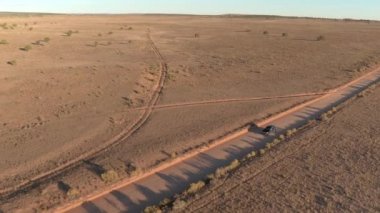 Anteni: boş tozlu yol yalak kuru çayır çöl Vadisi Utah güneşli sabahı araba siyah Suv araba. Uçan yukarıda altın günbatımında Capitol resif düz toprak yolu üzerinde seyahat jeep