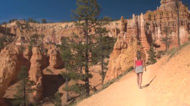 Tozlu yolda yürüyen genç kadın gezgin kumtaşı Hudu oluşumları Bryce Canyon Milli Parkı'nda güneşli Utah keşfetmek. Genç kadın turist tozlu yolun Bryce Canyon ABD hiking
