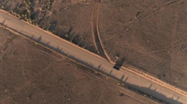 Anteni: boş tozlu yol yalak kuru çayır çöl Vadisi Utah güneşli sabahı araba siyah Suv araba. Uçan yukarıda altın günbatımında Capitol resif düz toprak yolu üzerinde seyahat jeep