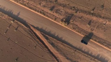 Anteni: boş tozlu yol yalak kuru çayır çöl Vadisi Utah güneşli sabahı araba siyah Suv araba. Uçan yukarıda altın günbatımında Capitol resif düz toprak yolu üzerinde seyahat jeep