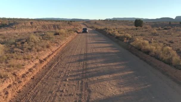 一对乘坐黑色 Suv 汽车在犹他州干燥的草地沙漠上沿着尘土飞扬的道路行驶 在金色日落时 乘坐吉普车在直达土路线上进入国会礁 — 图库视频影像