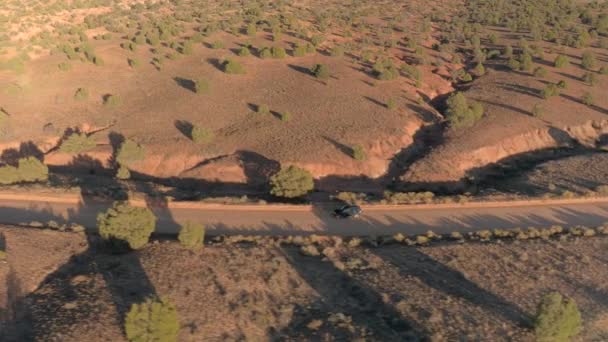 Suv 汽车在犹他州干燥的草地沙漠山谷中沿着尘土飞扬的空旷道路行驶 在金色日落时 乘坐吉普车在直达土路线上进入国会礁 — 图库视频影像
