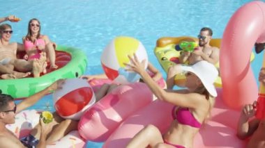 Ağır çekim yakın kadar mutlu gülümseyen öğrenciler bahar havuz partisinde renkli floaties fight su tabancası var. Şişme flamingo pizza karpuz ve halka eğlenceli neşeli genç insanların yok