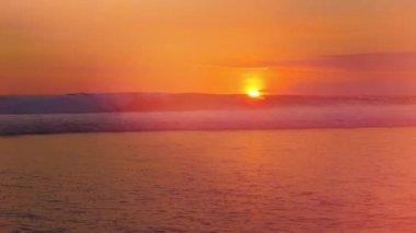 Mercek parlaması: kırma ve rüya gibi Bali Adası, Endonezya sakin yaz akşamı muhteşem kırmızı batımında deniz sahile doğru haddeleme büyük kıvırcık dalgalar. Altın ışık günbatımında sıçramasına deniz dalgalanan