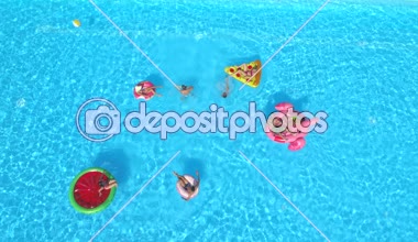 Hava: neşeli arkadaşları su havuz partisinde renkli floaties fight. Oynak çocuklar ve kız alma selfies şişme pizza, halka, flamingo ve karpuz yüzen üzerinde ve su sıçramasına