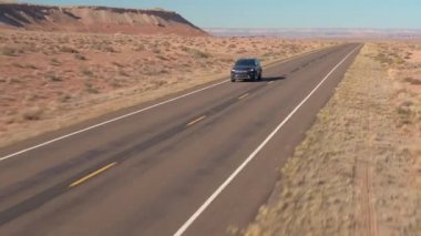 Hava yakın: Utah ABD bir boş yol yalak kumtaşı çöl boyunca bir siyah Suv araba yukarıda uçan. İnsanlar üzerinde yalak çöl manzara yerel otoyol güneşli günde seyahat yolculuğa.