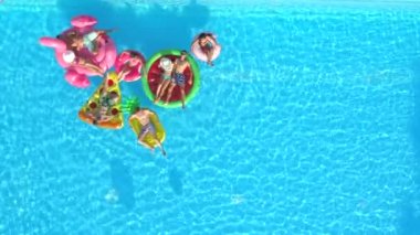 Hava kopya alanı: Oynak kızlar ve havuzunda renkli floaties sayıp. Yaz tatili şişme ananas, pizza, flamingo, karpuz ve halka yüzen zevk mutlu gülümseyen arkadaşlar