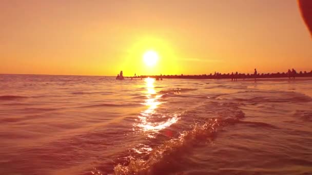 慢动作 镜头耀斑 细节的女性腿飞溅水滴在金色的灯光日落 享受暑假 美丽的日出时 海边洒海水的妇女 — 图库视频影像