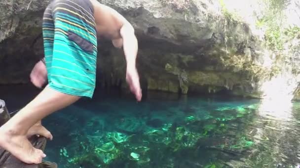 在阳光灿烂的墨西哥度假的年轻人潜入晶莹清澈的海水中 墨西哥大人坑中 身穿蓝色木板短裤的快乐男性首先跳入淡水中 — 图库视频影像