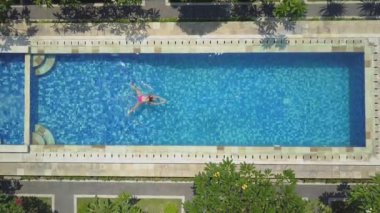Hava aşağı üst: yenileme ve sıcak güneşli günde açık havuzu suda yüzen yaz tatilde tanınmaz halde kadın. Kız pembe bikini lüks yüksek sınıf Resort boş havuzda zevk