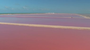 Hava: pembe deniz suyu ile dolu muhteşem tuz buharlaşma gölet üzerinde uçan. Ufukta mavi okyanus manzaralı saltworks. Yucatan Yarımadası kenarındaki doğal manzara izlerken kız