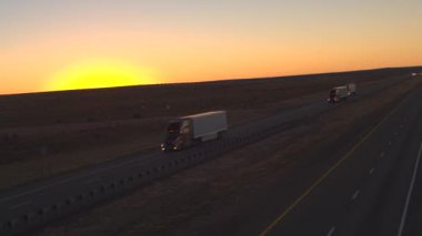 Hava yakın: otomobil ve navlun yarı kamyon dolu ile boş bir karayolu boyunca sürüş ürünler şafakta kargo taşıma. Konteyner kamyon teslim taşıyıcı kargo altın günbatımında çekme.