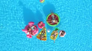 Hava üst aşağı neşeli kızlar ve çocuklar top havuzunda renkli floaties Tarih ile oynamıyor. Gülümseyen arkadaşlar, şişme ananas, pizza, flamingo, karpuz yaz tatili zevk halka yüzen