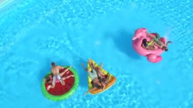 Hava: neşeli arkadaşları su havuz partisinde renkli floaties fight. Oynak çocuklar ve kız alma selfies şişme pizza, halka, flamingo ve karpuz yüzen üzerinde ve su sıçramasına
