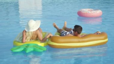 Yakın: Tanınmayan genç çift pizza ve ananas floaties havuzu üzerinde rahatlatıcı. Kız ve erkek arkadaşı döşeme yaz tatilde renkli yüzen eğlenceli ve sıcak güneşli günde ellerimi