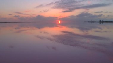 Çarpıcı tuz tava ve pembe günbatımında ufka uzanan tuz buharlaşma gölet üzerinde uçan hava. Salterns havzaları Meksika sahil sakin camsı su yüzey güzel gökyüzü yansıması