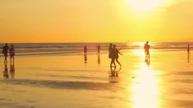 Kuta, Bali, Endonezya - 1 Mayıs 2017: turist keşfetmek muhteşem Bali Kuta Beach Altın ışık günbatımında kalabalık. Arkadaşlar selfies selfie-sopa, koşma, tatil keyfini insanların çocukları kullanarak alma