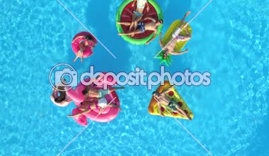 Hava aşağı üst: rahat kızlar ve havuzunda renkli floaties sayıp. Yaz tatili şişme ananas, pizza, flamingo, karpuz ve halka yüzen zevk mutlu gülümseyen arkadaşlar