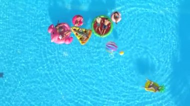 Hava üst aşağı neşeli kızlar ve çocuklar top havuzunda renkli floaties Tarih ile oynamıyor. Gülümseyen arkadaşlar, şişme ananas, pizza, flamingo, karpuz yaz tatili zevk halka yüzen