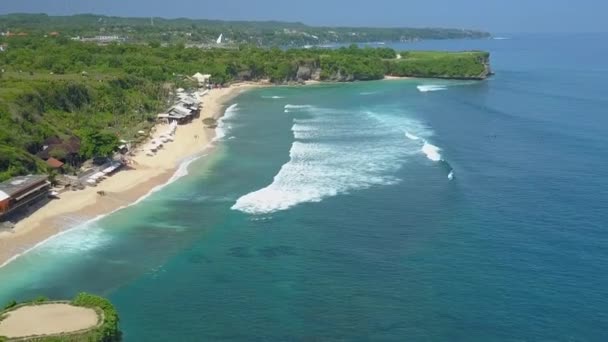 バリ島の日当たりの良い熱帯の夢のような白い砂バランガン ビーチ上空飛んで空中めまい効果 日光浴 泡波をキャッチ 楽園での休日を楽しんでいるサーファーの人の観光客 — ストック動画
