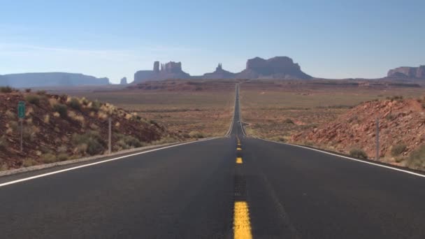 汽车沿着一条空旷的直道行驶 通往犹他州犹他州纪念碑谷的标志性屁股和梅萨山脉 游客前往令人惊叹的沙漠纪念碑谷地标景观 — 图库视频影像