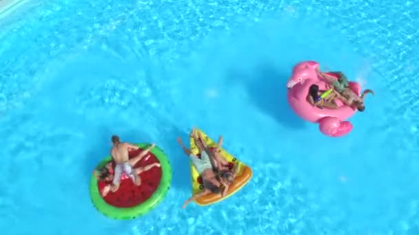 在泳池聚会上 在五颜六色的浮雕上打水的快乐朋友 好玩的男人和女孩泼水 自拍充气比萨饼 甜甜圈 火烈鸟和西瓜漂浮 — 图库视频影像