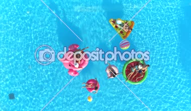 Hava aşağı üst: su silah olan arkadaş kavga havuz partisinde renkli floaties üzerinde. Oynak çocuklar ve su ve hava ile şişirilen pizza, halka, flamingo ve karpuz yüzen üzerinde eğlenmek kızlar