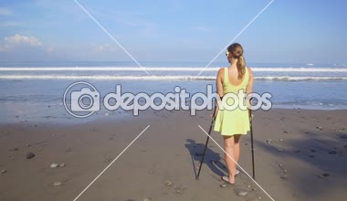 Koltuk değneği ile yaz plaj tatil seyahat yakın kaygısız kadar güçlü bağımsız kadın. Tatil zevk kumlu kıyıda duran kız. Erkek hiçbir endişe ve iyi sağlık sigortası ile güvenli