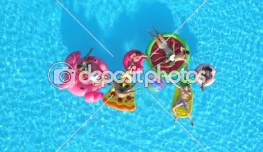 Hava üst aşağı neşeli kızlar ve çocuklar top havuzunda renkli floaties Tarih ile oynamıyor. Gülümseyen arkadaşlar, şişme ananas, pizza, flamingo, karpuz yaz tatili zevk halka yüzen