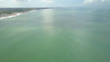 Hava: Bali, Endonezya kumsalda kalabalık sörf ve Canggu köyü uçan. Sırada bekleyen, sörf tahtaları üzerinde rahatlatıcı deniz insanlar. Surfboarders olmadan herhangi bir dalgalar sakin okyanusta yüzen