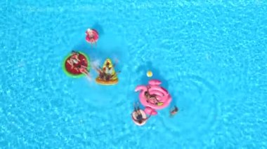 Hava: neşeli arkadaşları su havuz partisinde renkli floaties fight. Oynak çocuklar ve kız alma selfies şişme pizza, halka, flamingo ve karpuz yüzen üzerinde ve su sıçramasına