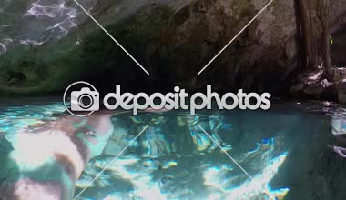 Slow Motion Close Up, Sualtı: Genç bir kadın kadim bir mağaranın nefes kesici güzelliğini keşfediyor ve dalıyor. Gizemli Grand Cenote obruğunda, berrak yeraltı sularında yüzen kız.